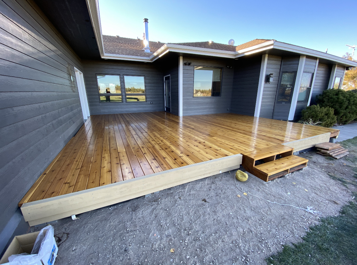 Freshly stained cedar deck with a glossy finish behind a Redmond home