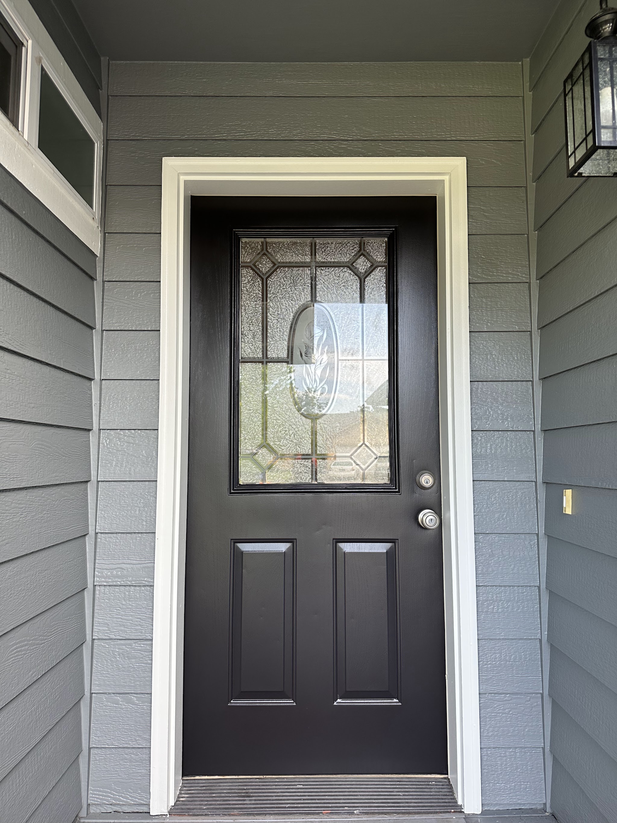 Close-up of a freshly painted matte black front door with white trim, a Midway Painting And Design job